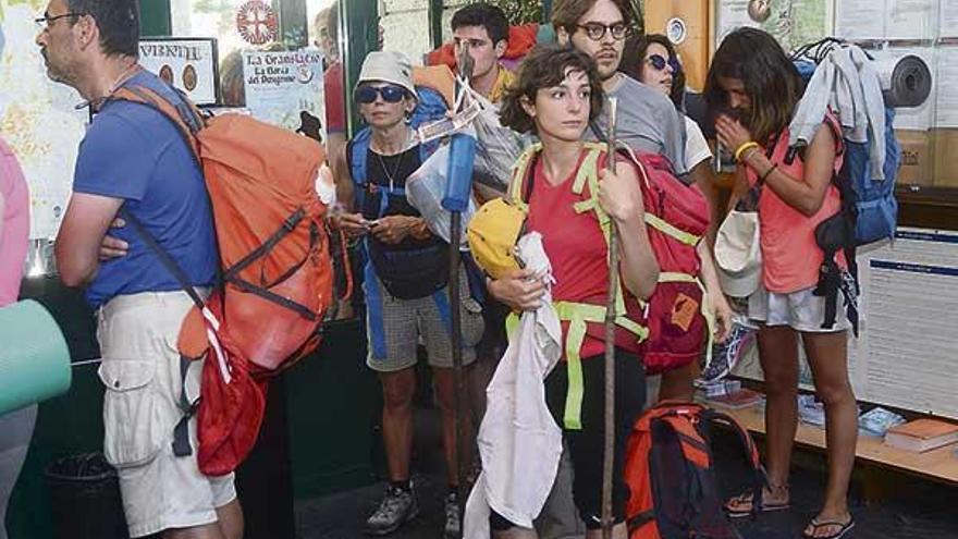 Varios peregrinos hacen cola en la recepción del albergue de la ciudad, ayer.  // R. Vázquez