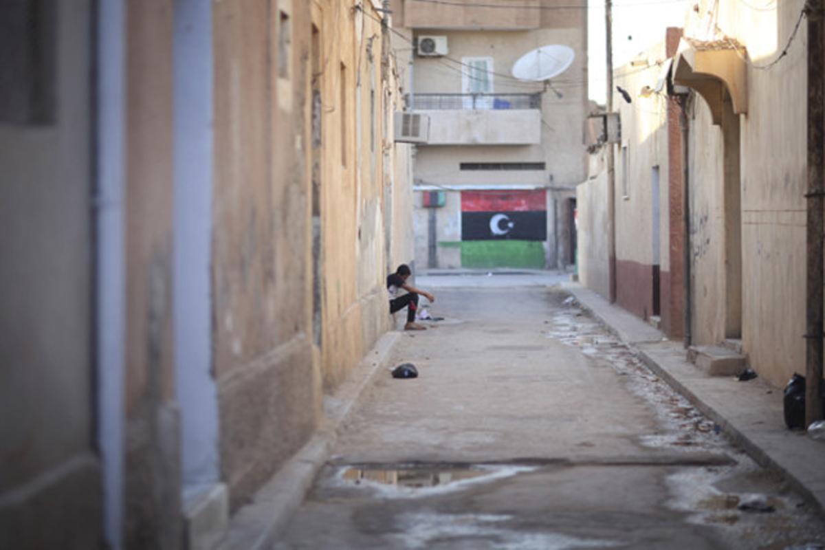 Un jove libi descansa en un portal al costat d’una pintada a favor de Gaddafi a la ciutat rebel de Bengasi, a Líbia.