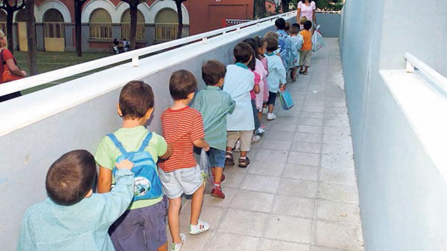 Varios niños en fila en la entrada de un colegio.