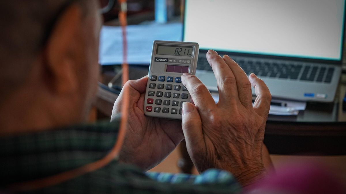 Un hombre revisa facturas y echa cuentas con una calculadora.