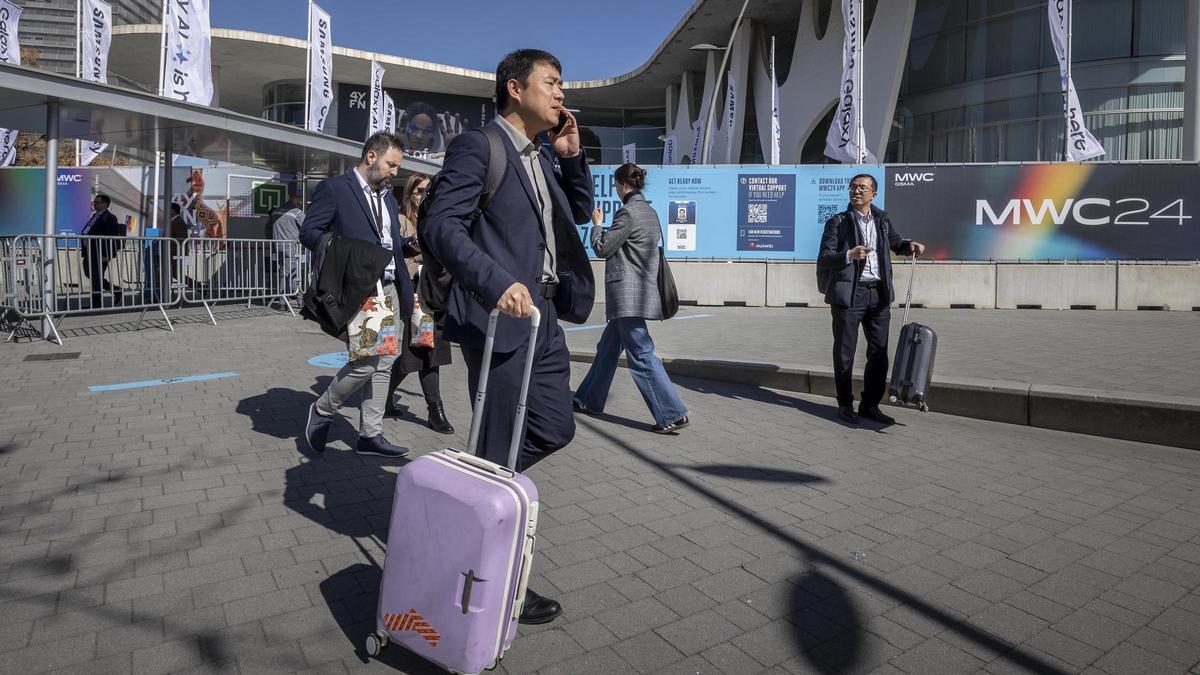 Asistentes al Mobile World Congress abandonan el recinto de la Fira en l'Hospitalet.