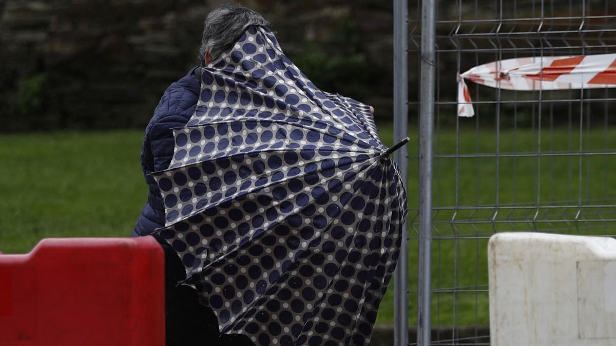 Una mujer lucha contra el viento para mantener su paraguas en pleno temporal