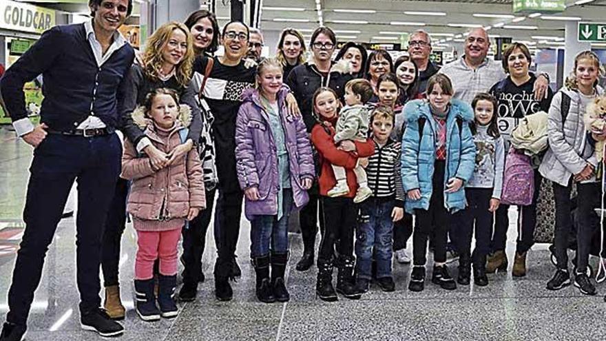 Los menores posan junto a sus familias de acogida, ayer en el aeropuerto.