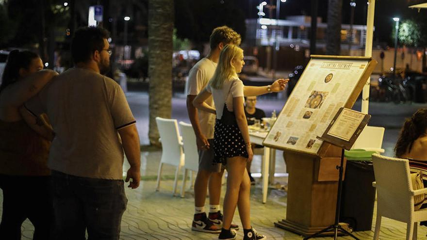 Unos jóvenes observan la carta de un restaurante de Sant Antoni