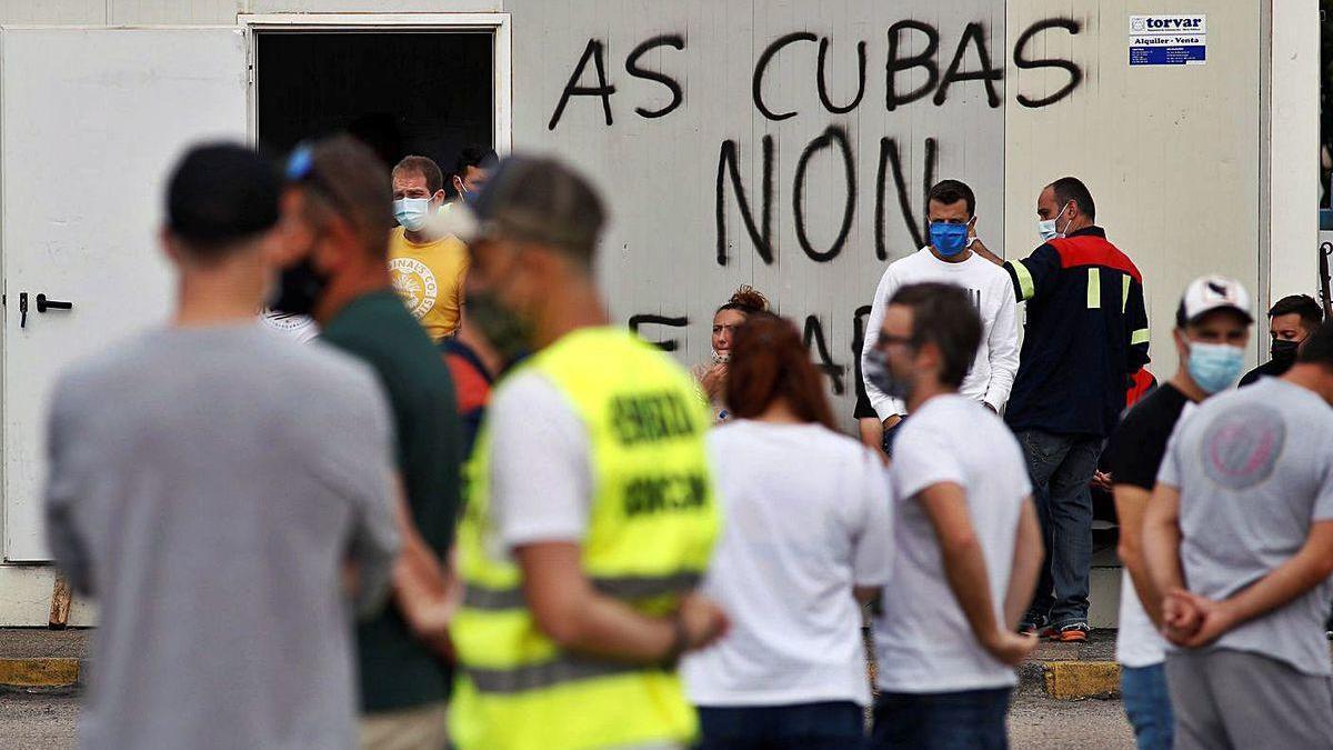 Trabajadores en la entrada de San Cibrao, ayer, donde puede leerse &#039;As cubas non se paran&#039;.