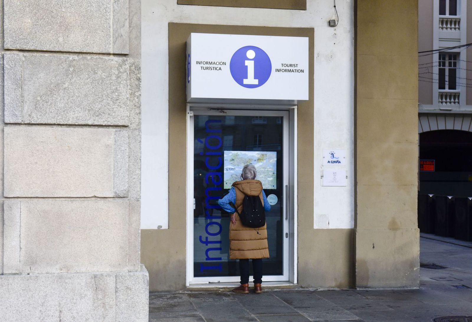 Una mujer consulta un mapa en la puerta de la oficina de turismo de María Pita. | Casteleiro