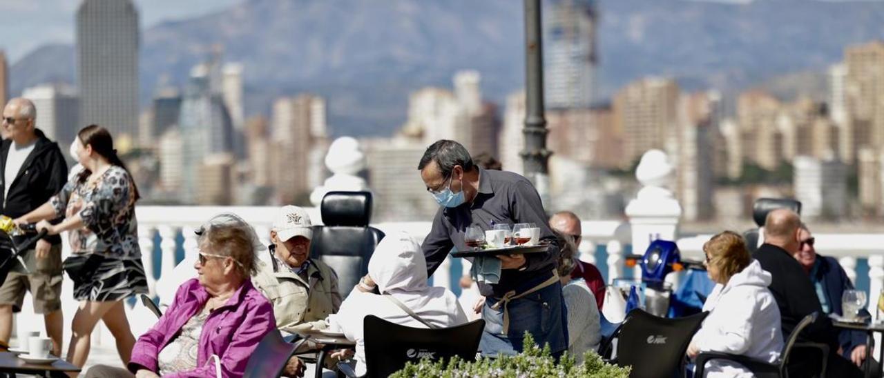 Un camarero sirve en una terraza llena en Benidorm.