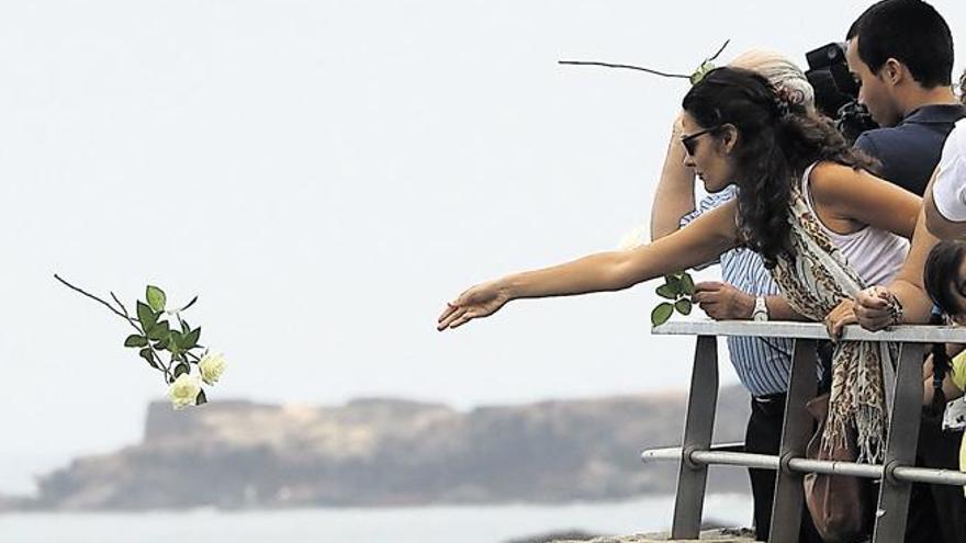 Una joven arroja unas rosas blancas al mar durante el homenaje a las víctimas de Spanair celebrado ayer en Las Canteras. |