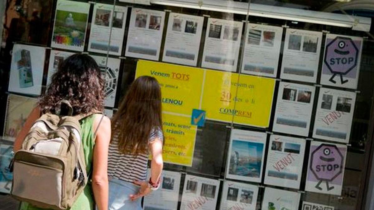 Dos jóvenes miran los anuncios de una inmobiliaria.