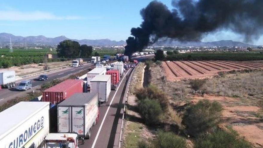 Colas, con el camión incendiado al fondo