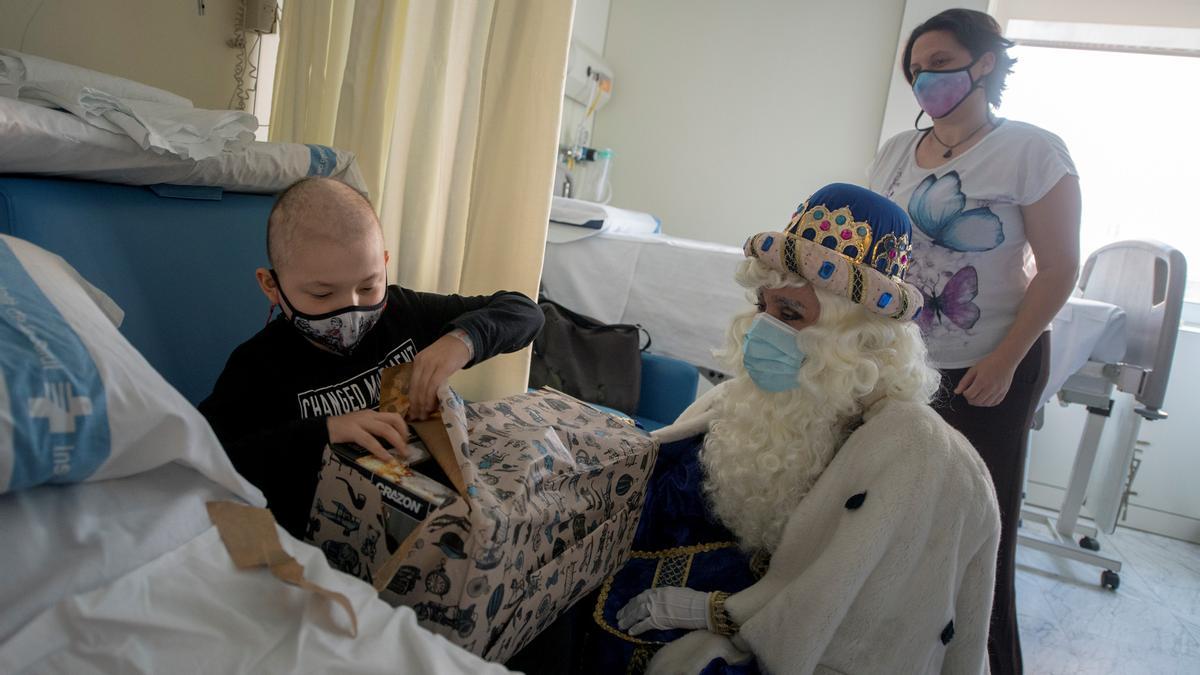 Barcelona. 06.01.2023. Sociedad. Los Reyes Magos visitan a los niños ingresados en el hospital Vall Hebrón, en la foto Joan de ocho años recuperándose en la planta de pediatría oncológica recibiendo su regalo de manos del rey Melchor, durante la festividad de Reyes. Fotografía de Jordi Cotrina