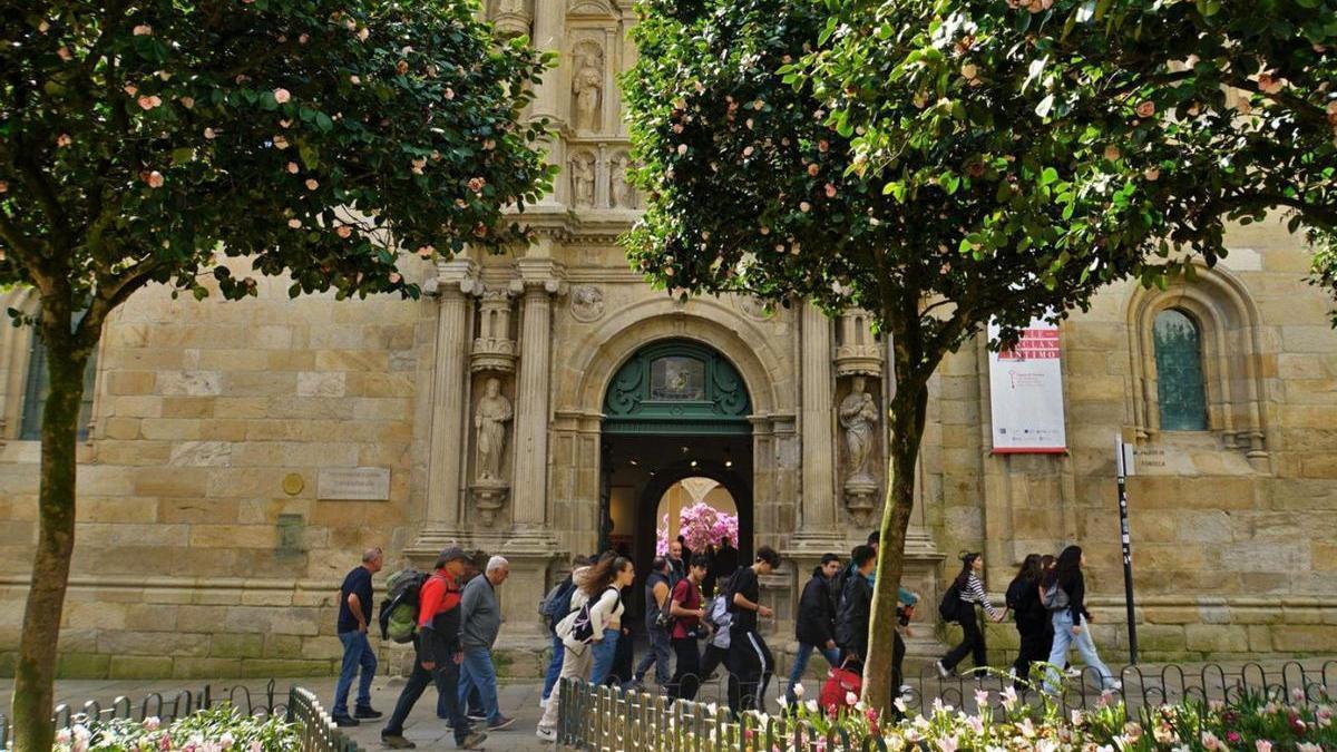 Persoas pasando diante do Pazo de Fonseca, en Santiago de Compostela