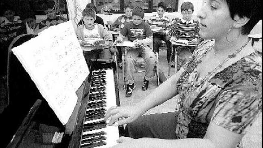 Una profesora imparte clases de piano en la Casa de la Música de Mieres, con sus alumnos al fondo.