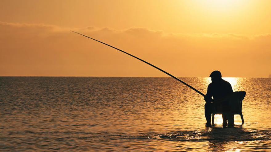 Un hombre pesa a la orilla del mar.