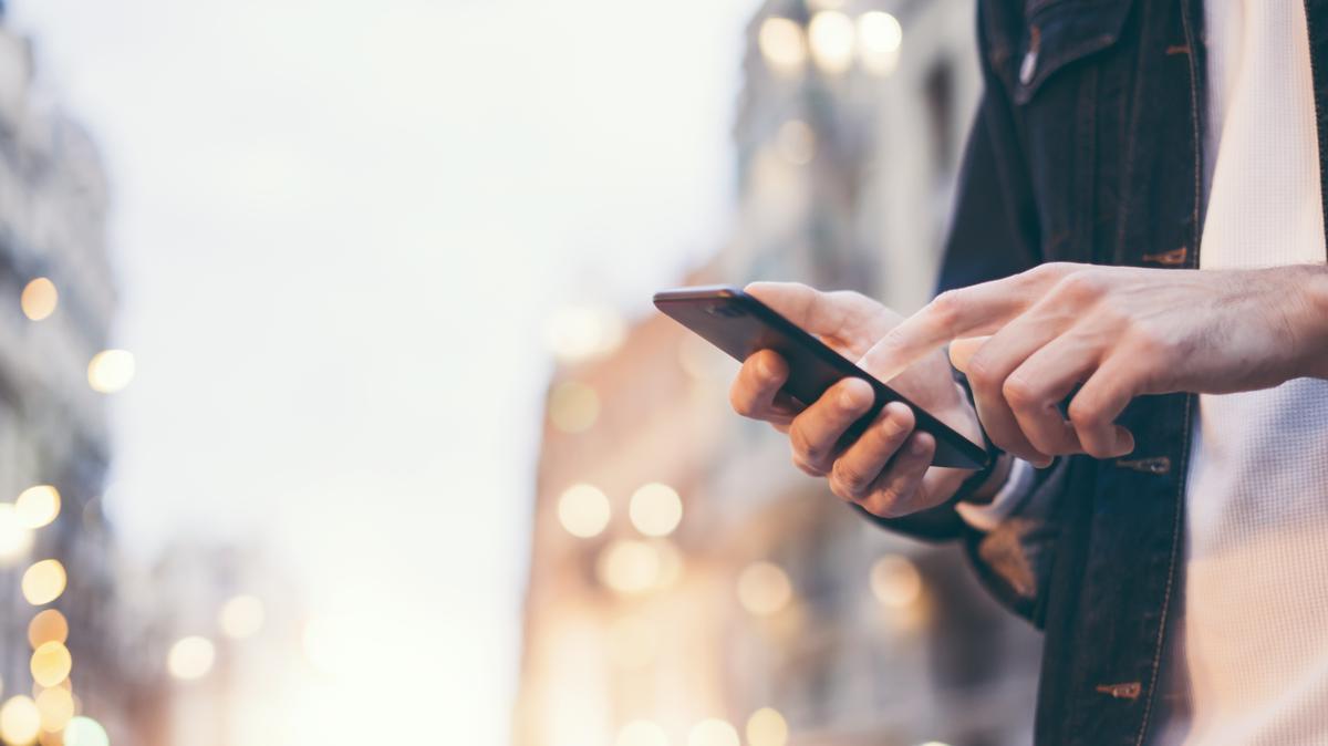 Un joven consulta su teléfono móvil.