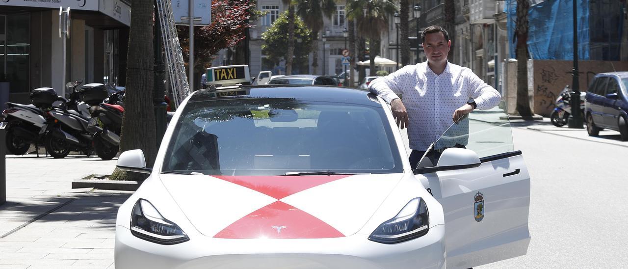 Julio Sousa posa con su taxi de la marca Tesla.