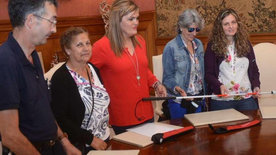 La Diputada Digna Rivas (centro) recibe el bastón blanco y rojo de María Jesús Monterde (dcha). // R. V.
