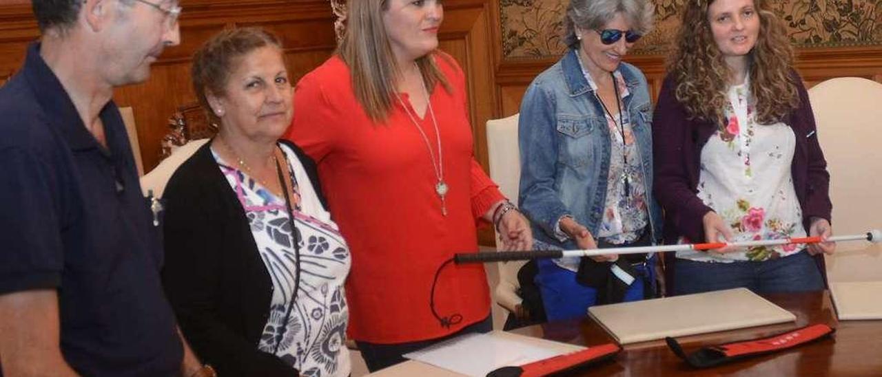 La Diputada Digna Rivas (centro) recibe el bastón blanco y rojo de María Jesús Monterde (dcha). // R. V.