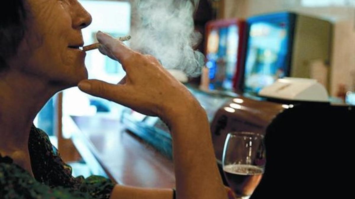 Una mujer fuma un cigarrillo en la barra de un bar de Barcelona, ayer por la tarde.