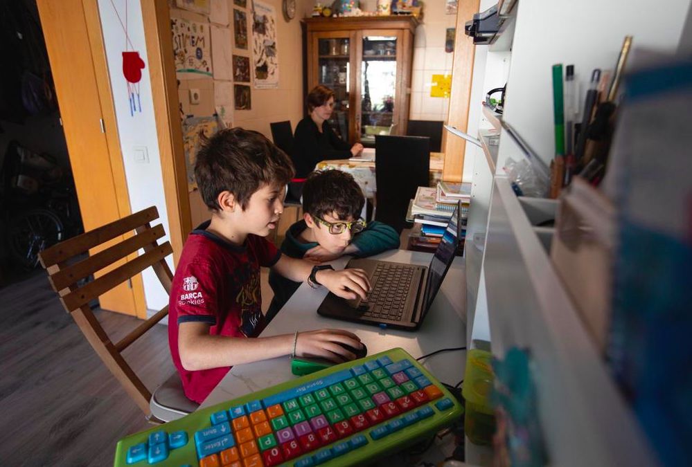 Una madre teletrabaja en casa mientras sus hijos juegan con el ordenador, esta mañana en Barcelona