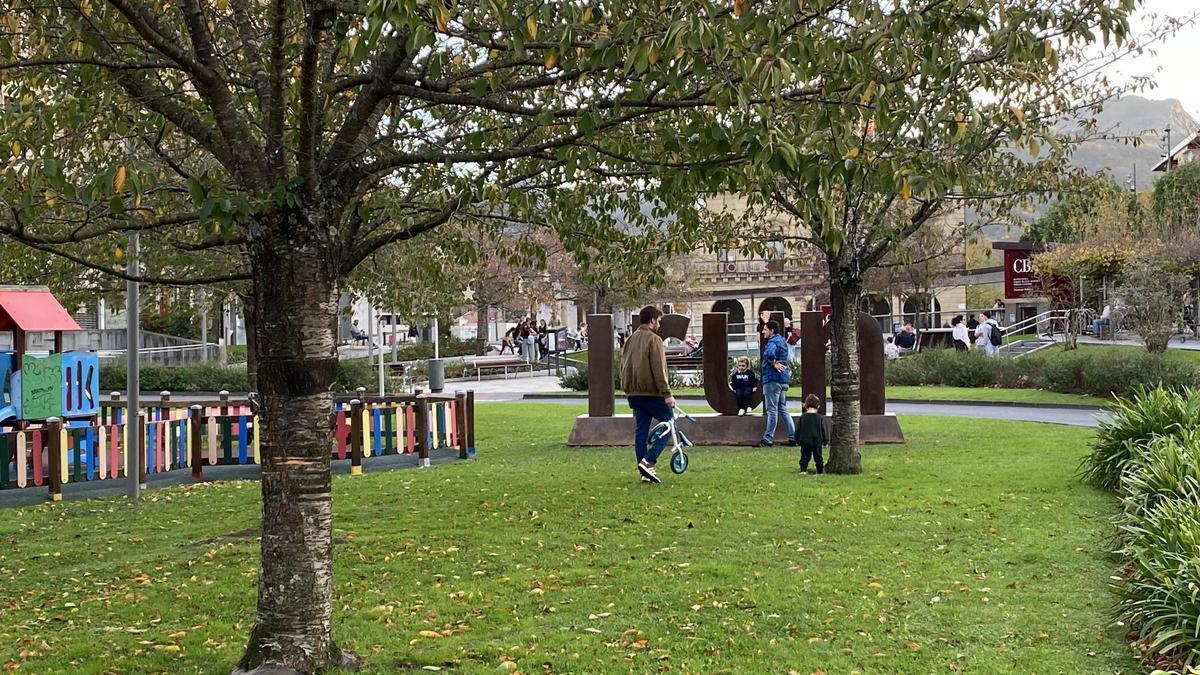 Varios padres juegan con sus hijos en un parque.