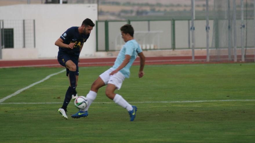 El jugador del UCAM Iván Pérez trata de superar a un futbolista del Jumilla.