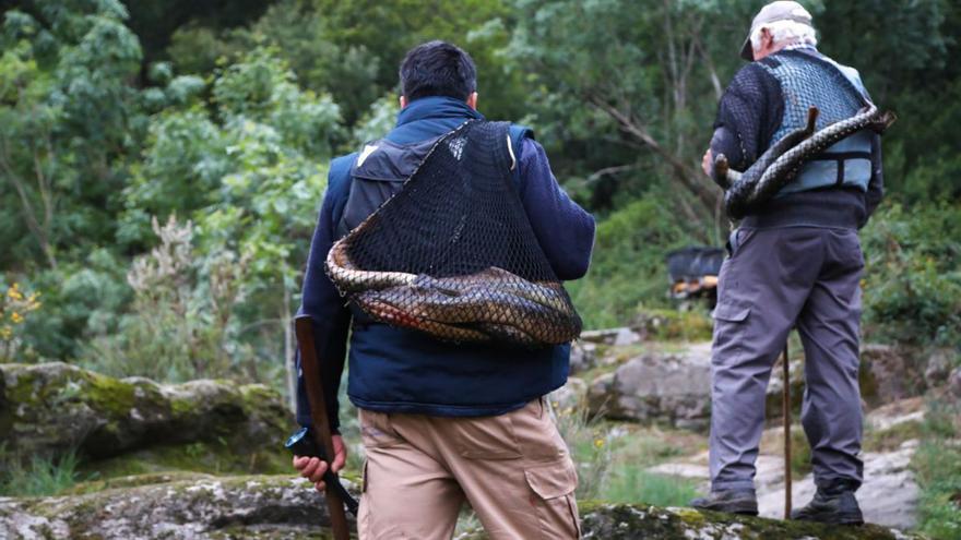 Pescadores de lamprea con los ejemplares a sus espaldas.