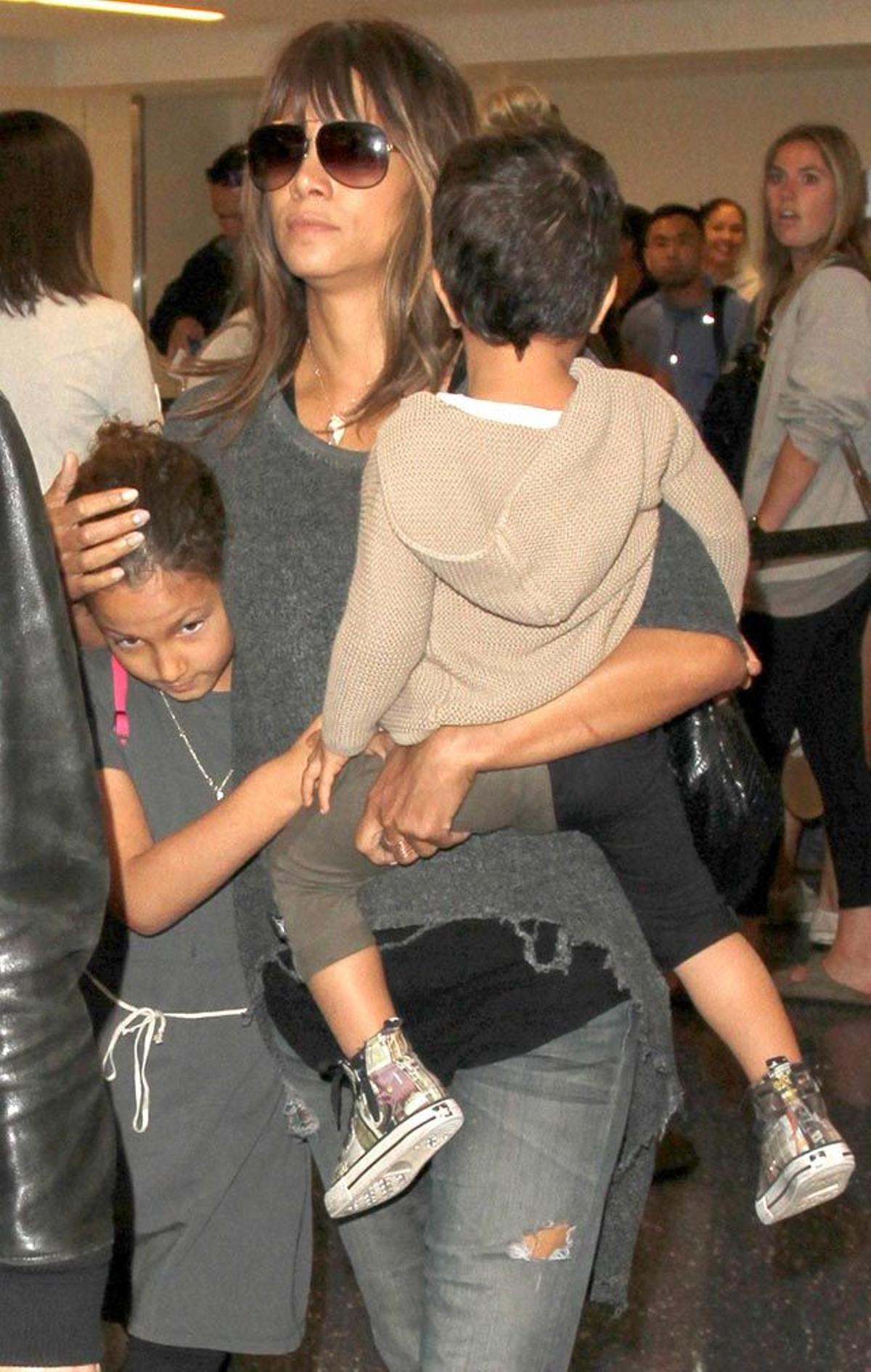 Halle Berry protege a sus niños mientras caminan por la terminal del aeropuerto.