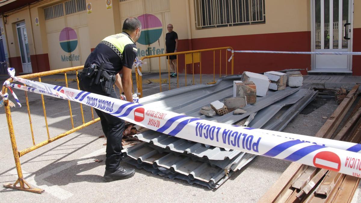 Un  agente de la Policía Local apilando las placas metálicas y los escombros.