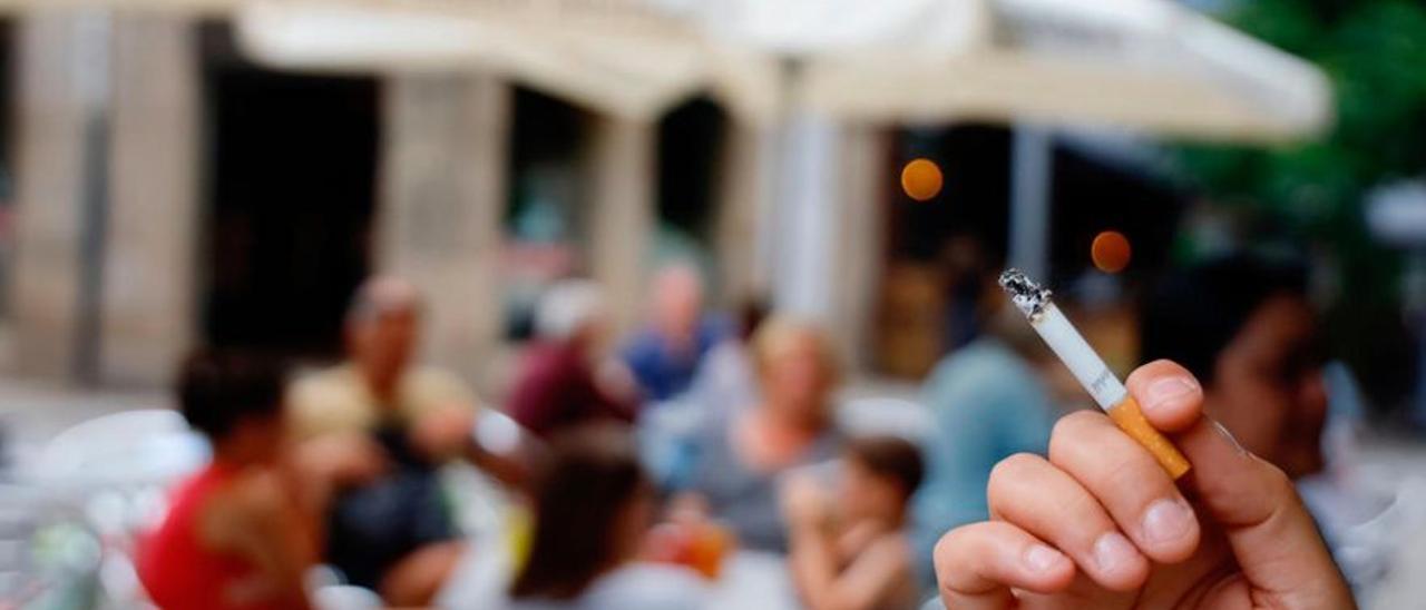 Una persona fuma con una terraza al fondo.