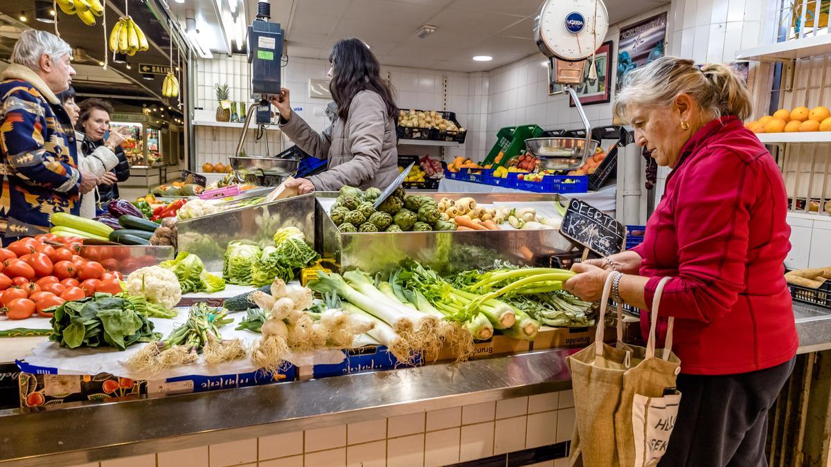 Una mujer comprando verduras en uno de los puestos del Mercado Central de Alicante.