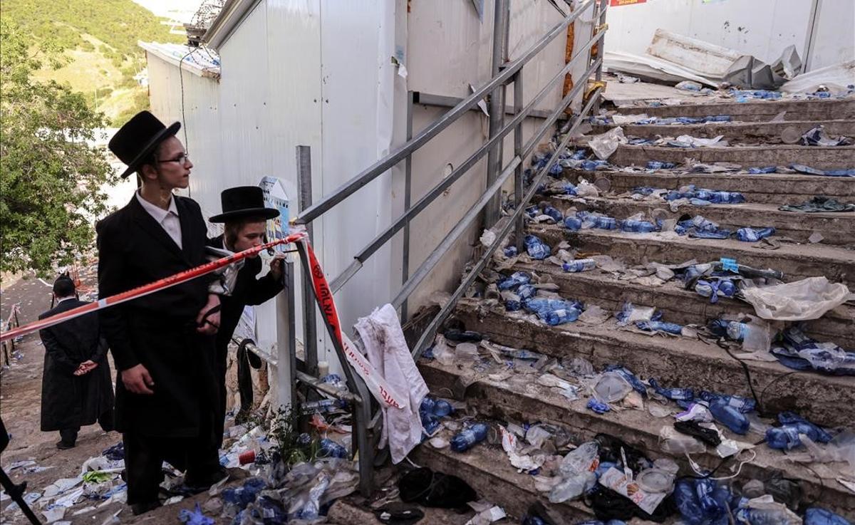 Judíos ultraortodoxos contemplan unas escaleras llenas de escombros y restos personales, en el Monte Meron, tras la avalancha.