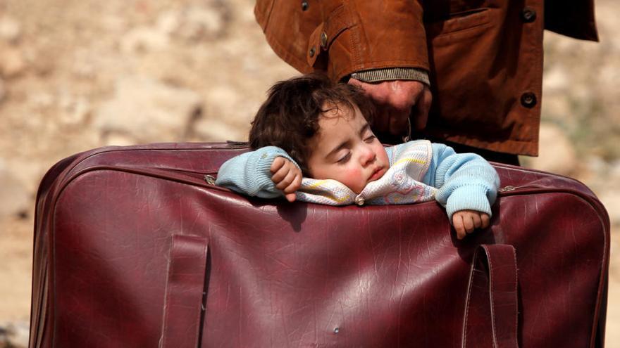 Un hombre traslada a un bebé en una maleta en Guta (Siria).