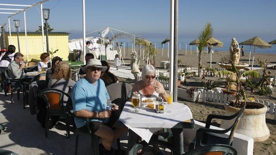 Varios turistas disfrutan de la gastronomía malagueña en un chiringuito de la Costa.