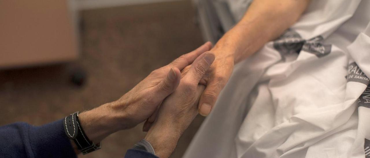 Una mujer es acariciada por su marido minutos antes de que ella culmine el proceso para morir por eutanasia.