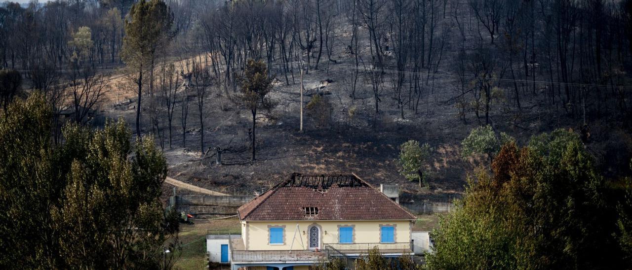 Una casa, con el tejado parcialmente quemado, en el núcleo de A Veiga de Cascallá (Rubiá), tras el paso del incendio originado en Carballeda de Valdeoras. |   // BRAIS LORENZO