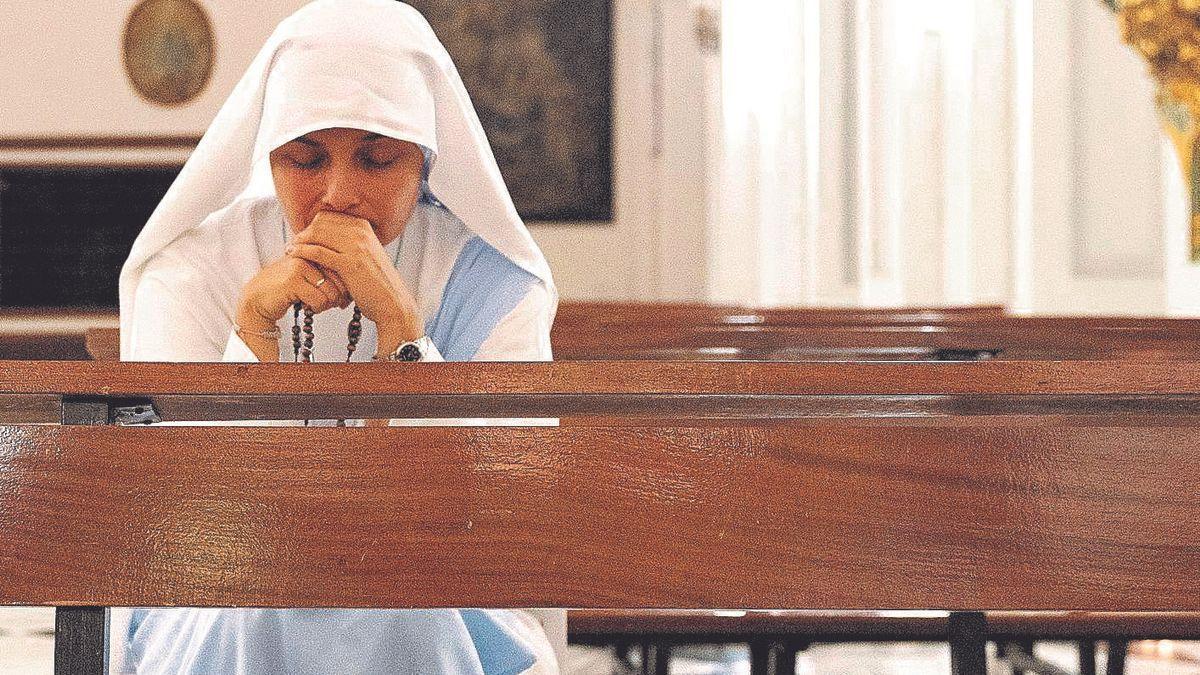 Ser comunicadoras en el siglo XXI no está reñido con conservar las tradiciones: una joven hermana reza, rosario en mano, en el templo.