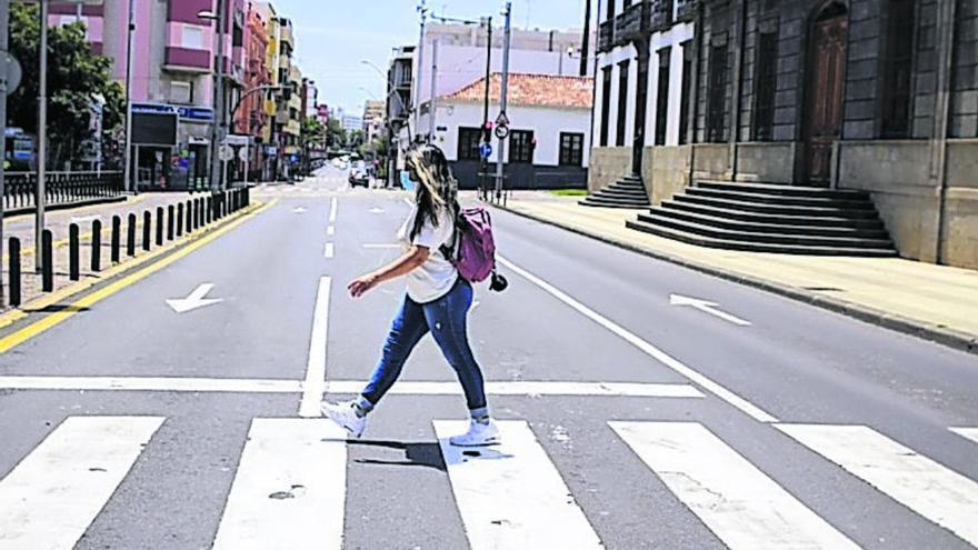 Una joven cruza un paso de peatones desértico en Santa Cruz de Tenerife.