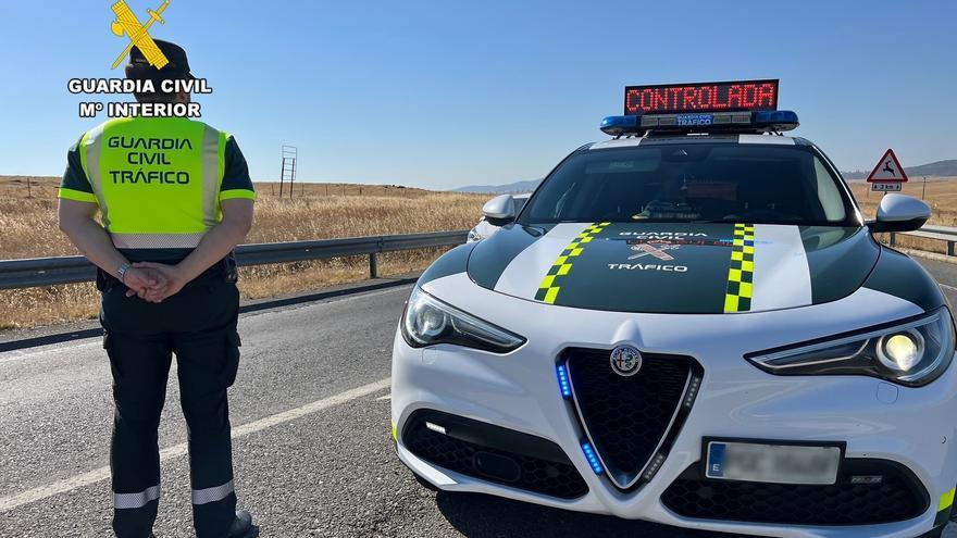 Archivo - Un agente de la Guardia Civil de Tráfico junto a su vehículo en una carretera.