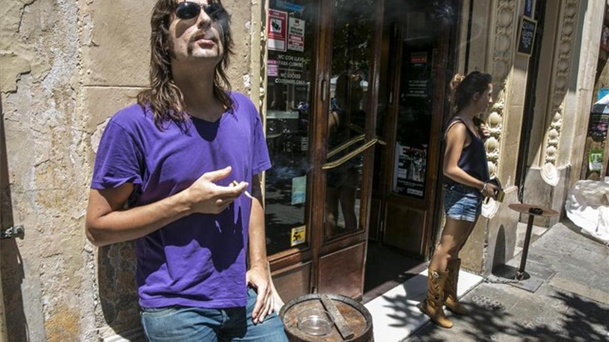 Dos personas fuman junto a la puerta de un establecimiento de Barcelona, ayer.