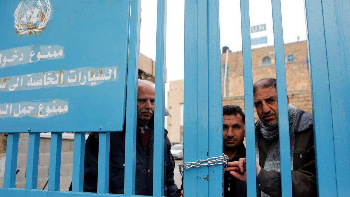Un grupo de palestinos detrás de la valla de la oficina de la agencia de la ONU para los refugiados palestinos (UNRWA) durante una protesta en la ciudad de Cisjordania.