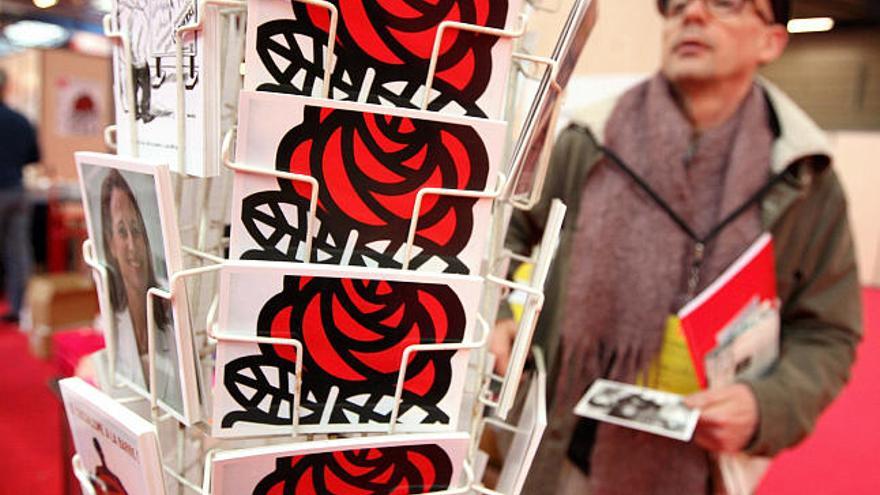 Un hombre observa unas postales del 75 Congreso del Partido Socialista (PS) francés que comienza hoy, viernes 14 de noviembre en Reims, Francia. Rodeado de incertidumbres y disputas internas, el tema principal será la discusión de quien será el próximo en tomar el mando del partido.