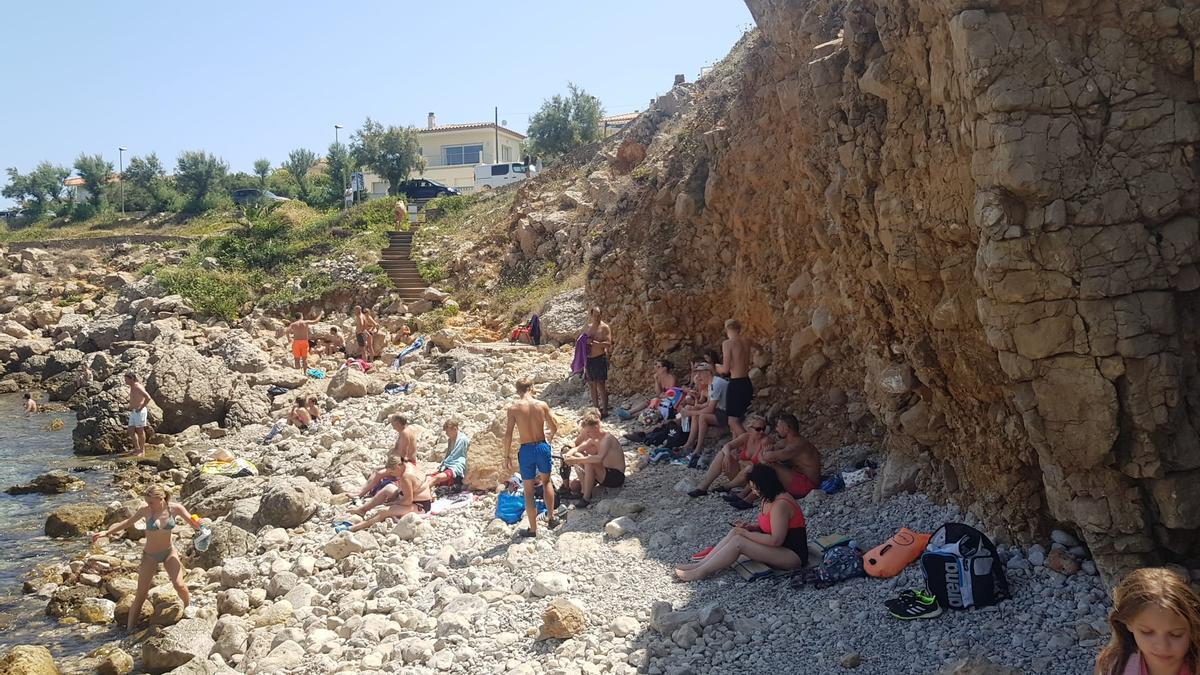 Bañistas en la playa de L'Escala cerrada por desprendimientos.