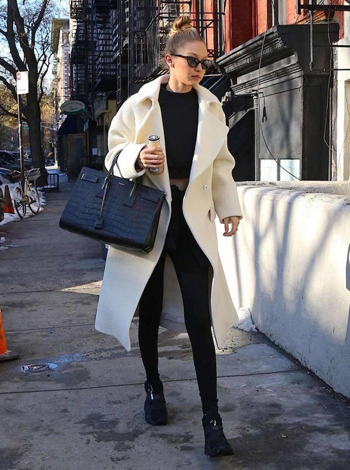 Gigi Hadid con moño alto, abrigo blanco y prendas negras