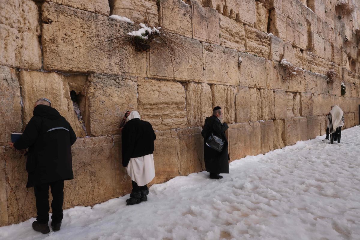 Oraciones en el Muro de las lamentaciones de Jerusalén, cubierta por un manto de nieve.