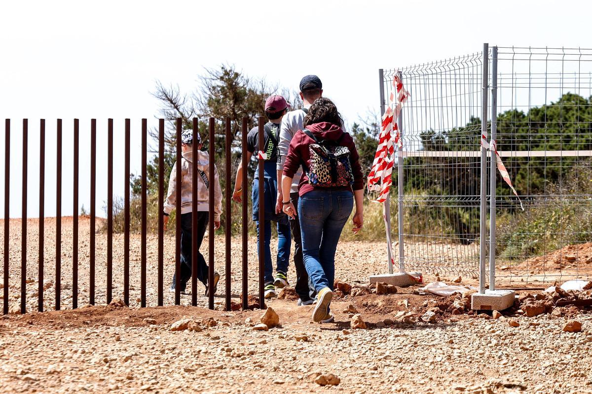 Un grupo de gente pasa al lado del vallado metálico instalado en el Centro de Interpretación de sa Caleta.