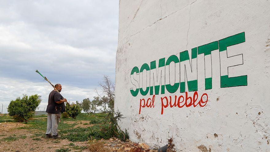 Uno de los jornaleros, ante la pintada que reivindica la finca.