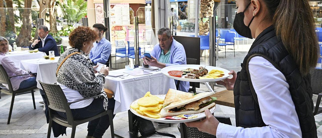 Una camarera sirve dos platos en la terraza de uno de los restaurantes que se encuentran situados en la Glorieta. | MATÍAS SEGARRA