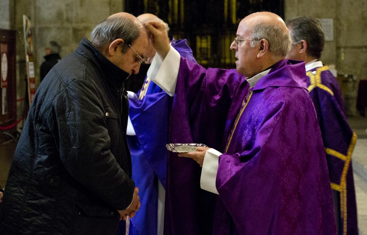 Sacerdote imponiendo la ceniza en la frente de un cristiano que asiste a la celebración del Miércoles de Ceniza.