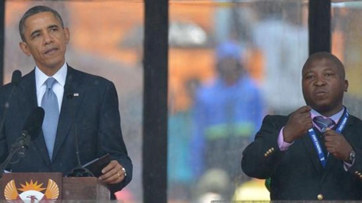 Obama junto al falso intérprete de la lengua de signos, en el escenario del estadio de Soweto, este martes.